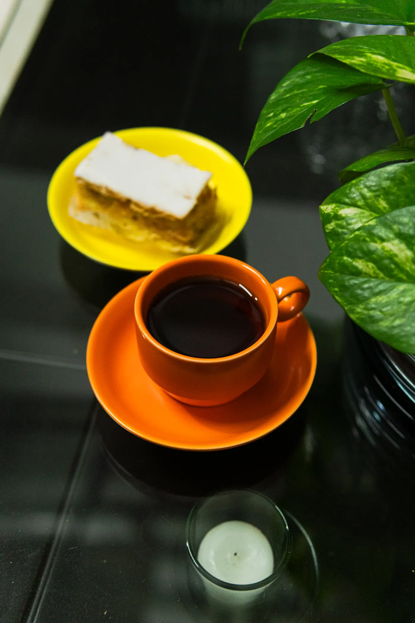 Taza de café Innana servida junto a un postre y una planta