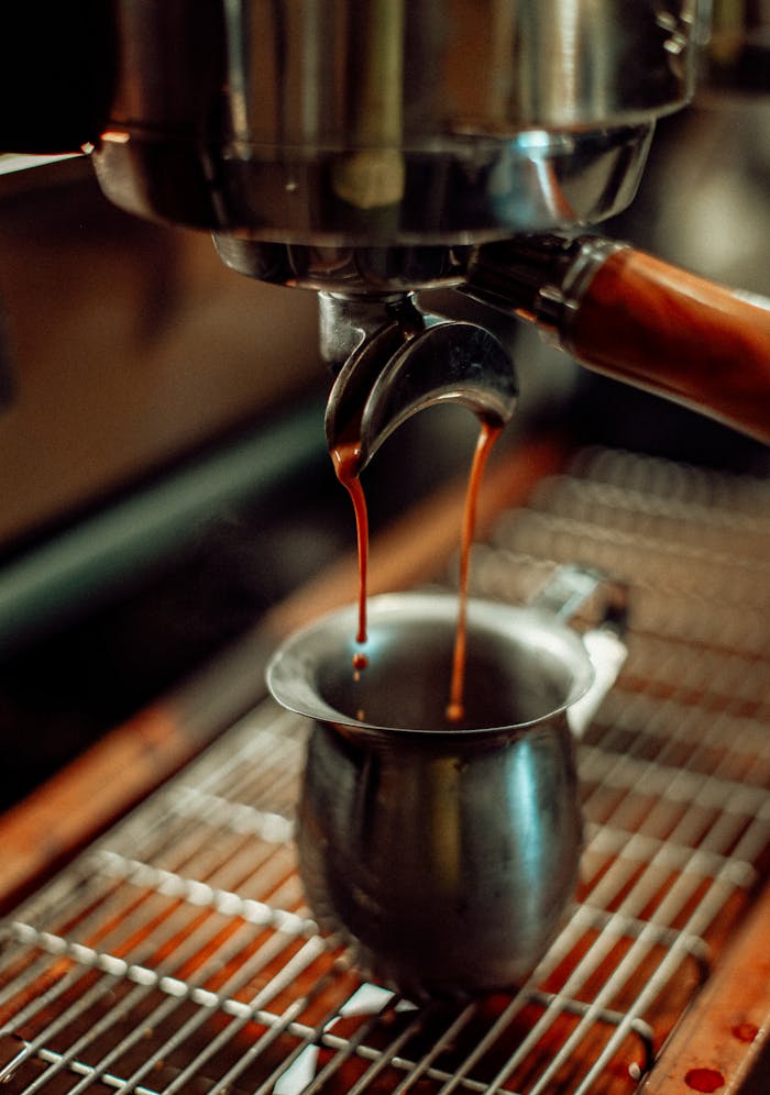 our-experience Close-up of espresso pouring from a machine into a metal cup in a Baku coffee shop.