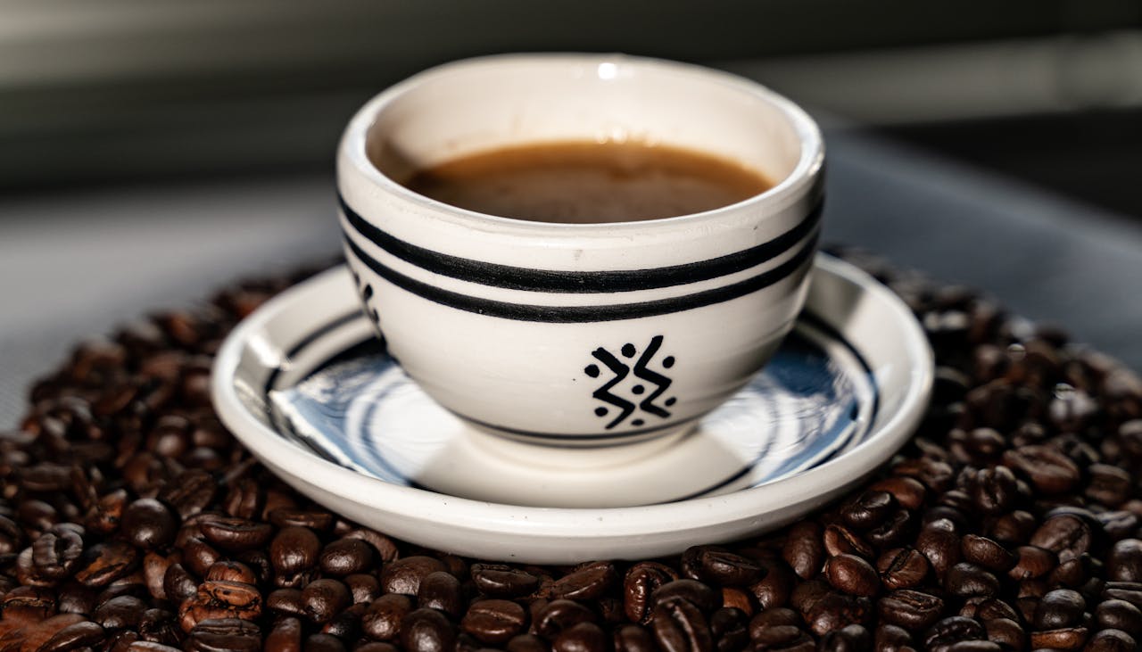 Artisan coffee served in a decorative ceramic mug surrounded by beans, ideal for cozy cafe vibes.