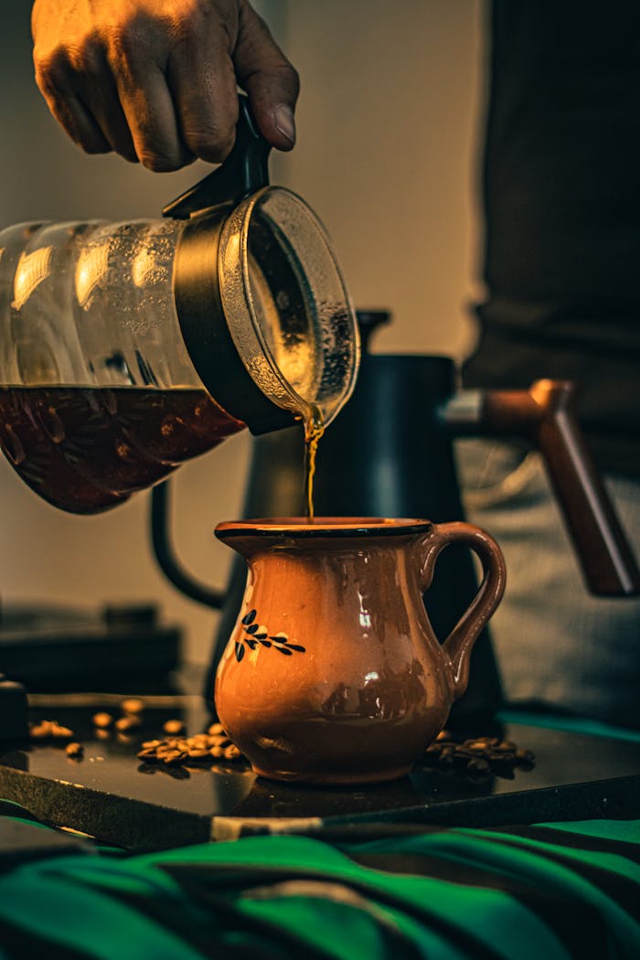 ours-journey A cup of freshly brewed coffee being poured into a ceramic mug in a warm, inviting ambiance.
